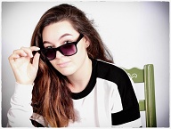 Cool teenage girl looks over her sungalsses at camer